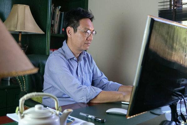 Work from home concept. Asian Chinese businessman working on the computer in his study room.
