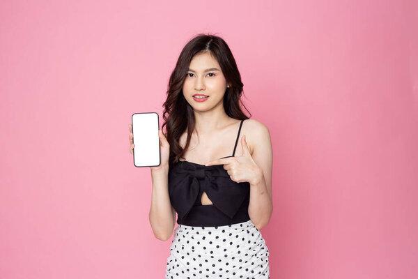 Cheerful smiling Asian woman holding smartphone isolated on pink background.with clipping pat