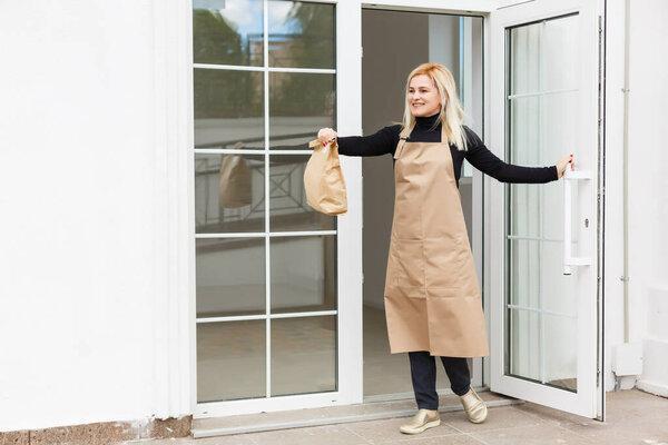 Woman in apron packaging products in paper bags for sale in workshop. Small business concept.
