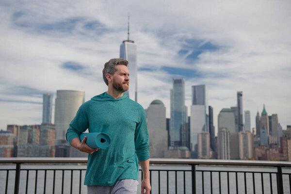 健康的男人在曼哈顿附近锻炼。健康的运动。活跃的老年人正在室外锻炼身体.退休后练习。成熟的退休运动员做伸展运动