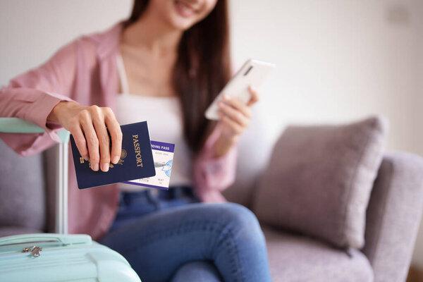年轻的亚洲成年女性在激动人心的国际旅行前组织旅行证件移动设备行李箱。预期假期.