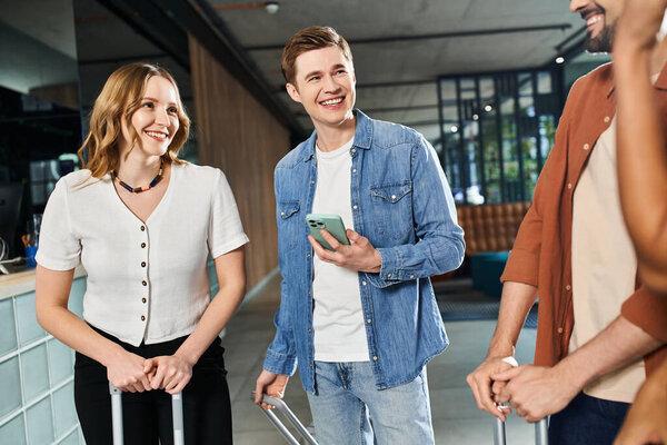 Multicultural colleagues in casual attire standing together in a hotel lobby during a corporate trip.