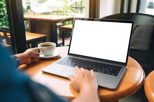 Mockup image of a woman using and touching on laptop touchpad with blank white desktop screen while drinking coffee