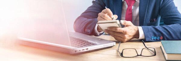 man working in notepad and computer in office