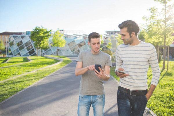 two multiethnic friends outdoors together using smart phone