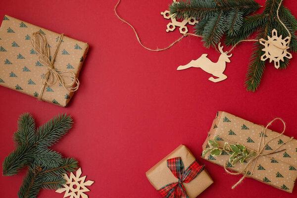Christmas holidays composition on red background with copy space for your text. Xmas tree fir branches with ball in the corners, gift box. Xmas backdrop for greeting card. Flat lay, top view, overhead