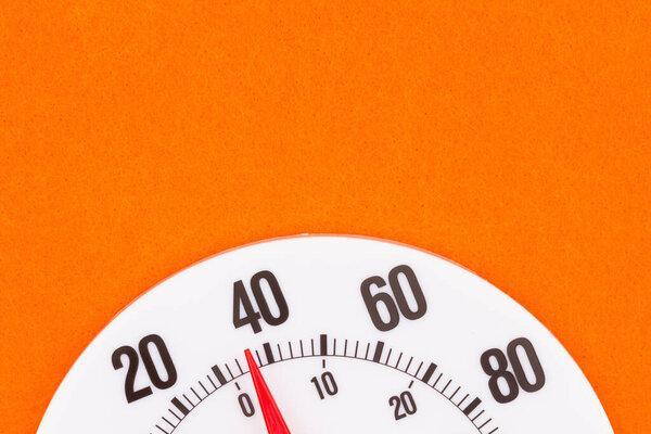 Closeup of a thermometer at 40 degrees with a bright orange background and with copy space for weather or temperature message