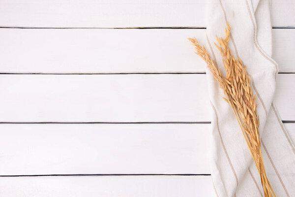 Top view of dry wheat leaves on white wooden background with copy space, mockup, place for product display