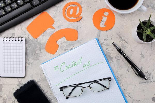 client support service. Contact us for feedback. Desktop with notepad and glasses and various feedback icons. top view